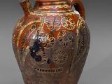 un vase marron orné de motifs sur un fond gris
