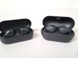 une photo montrant deux écouteurs noirs dans leur étui, posés sur une surface blanche