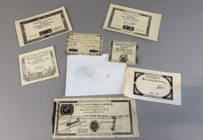 some old paper money sitting on top of a table next to a piece of paper