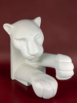 une sculpture blanche représentant un chat assis sur une surface rouge
