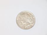 a silver coin on a white surface with a white background
