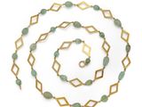 a close up of a long necklace with green beads on a white background