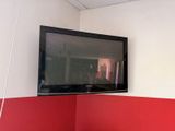 une télévision à écran plat fixée au mur au-dessus d'un lit