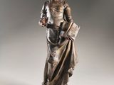 a bronze statue of a woman holding a book on a pedestal
