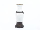 a white and black vase sitting on a black stand
