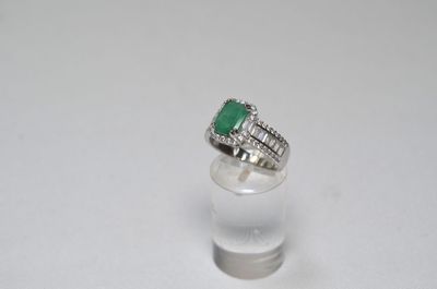 a close up of a ring with a green stone on top of a clear glass