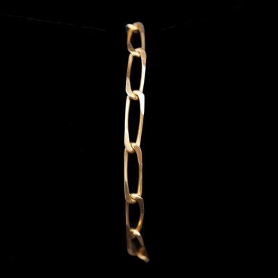 gros plan d'un bracelet en chaîne en or sur fond noir