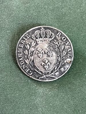 une pièce d'argent sur laquelle figure une couronne, posée sur un fond vert