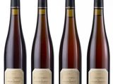 four bottles of wine sit side by side on a white surface