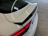 the rear end of a white car in a showroom with other cars in the background
