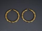 a pair of gold hoop earrings on a black background