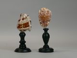 pair of carved glass vases on black pedestals against a gray background