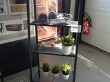 une étagère sur laquelle sont posées des plantes, dans un coin de la pièce