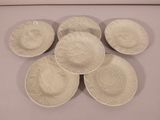 six white plates with designs on them are arranged on a table