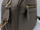 grey leather cross body bag with gold zippers on a white background