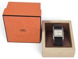 une boîte orange contenant une montre, posée sur une surface blanche
