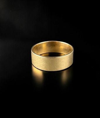 a gold wedding ring on a black surface