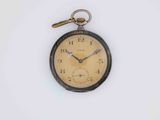an old pocket watch hanging on a white wall