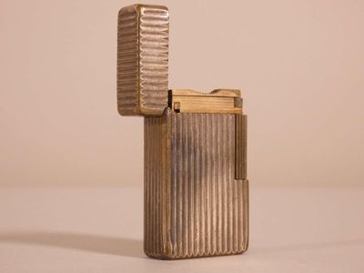 un étui à cigarettes en métal argenté posé sur une surface blanche