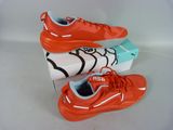 two pairs of orange sneakers are on a white surface with a box in the background
