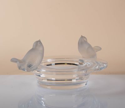 two birds sitting on a glass bowl on a table