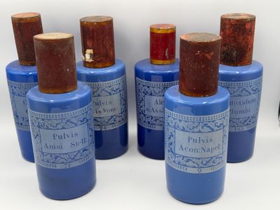 six flacons de parfum bleus et marron posés sur une surface blanche