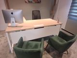 two green chairs in front of a desk with a computer on it