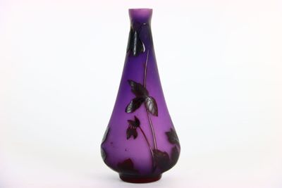 a purple vase with black leaves on it on a white background