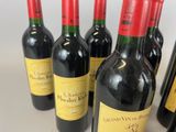 six bottles of red wine are lined up on a white surface