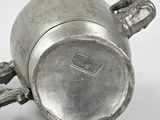 a silver cup with a handle on a white surface