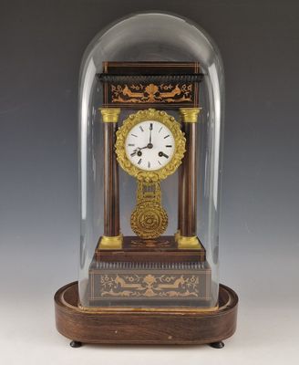 une petite horloge sous un dôme de verre sur une table