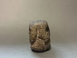 an image of a small stone statue of a man ' s face on a gray surface