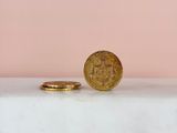 a gold coin sitting on top of a white table next to a pink wall