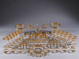 an assortment of gold and clear glass items on a white surface
