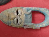 un masque en bois posé sur une surface rouge, à côté d'autres objets