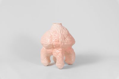 une petite figurine rose posée sur une surface blanche