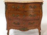 a small chest of drawers with marble top on it