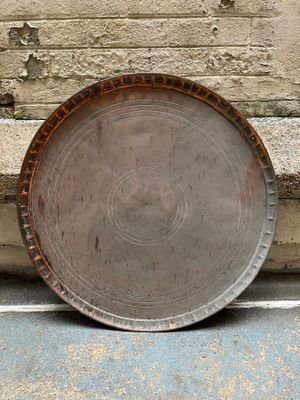 a large metal plate sitting on the ground next to a brick wall