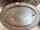 a wooden table with a round top on a tile floor
