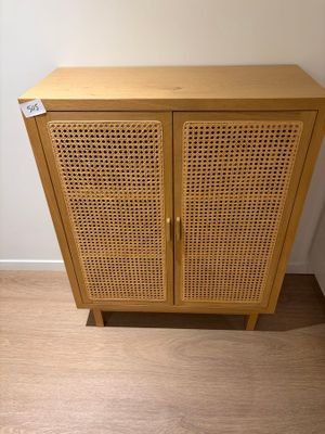 une armoire en bois munie d'une porte en rotin