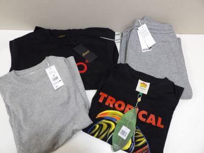 Trois t-shirts sont posés sur une table, avec leurs étiquettes encore attachées.
