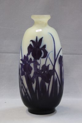 a white vase with purple flowers on it sitting on a table
