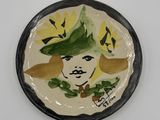 une assiette sur laquelle est représentée une femme portant un chapeau