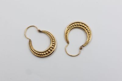 une paire de boucles d'oreilles en or sur fond blanc