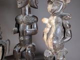 three wooden statues of people sitting next to each other on a table
