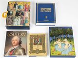Quatre livres sont posés sur une surface blanche ; l'un d'entre eux est bleu et un autre est doré.