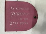 un livre rose sur lequel sont inscrits des mots, posé sur une table