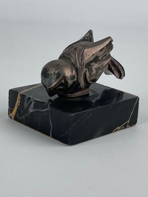 statue représentant un poisson posée sur un socle en marbre, sur fond blanc