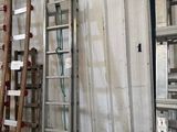 Plusieurs échelles sont alignées contre un mur dans un entrepôt.