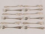 six silver spoons and two silver spoons on a white surface